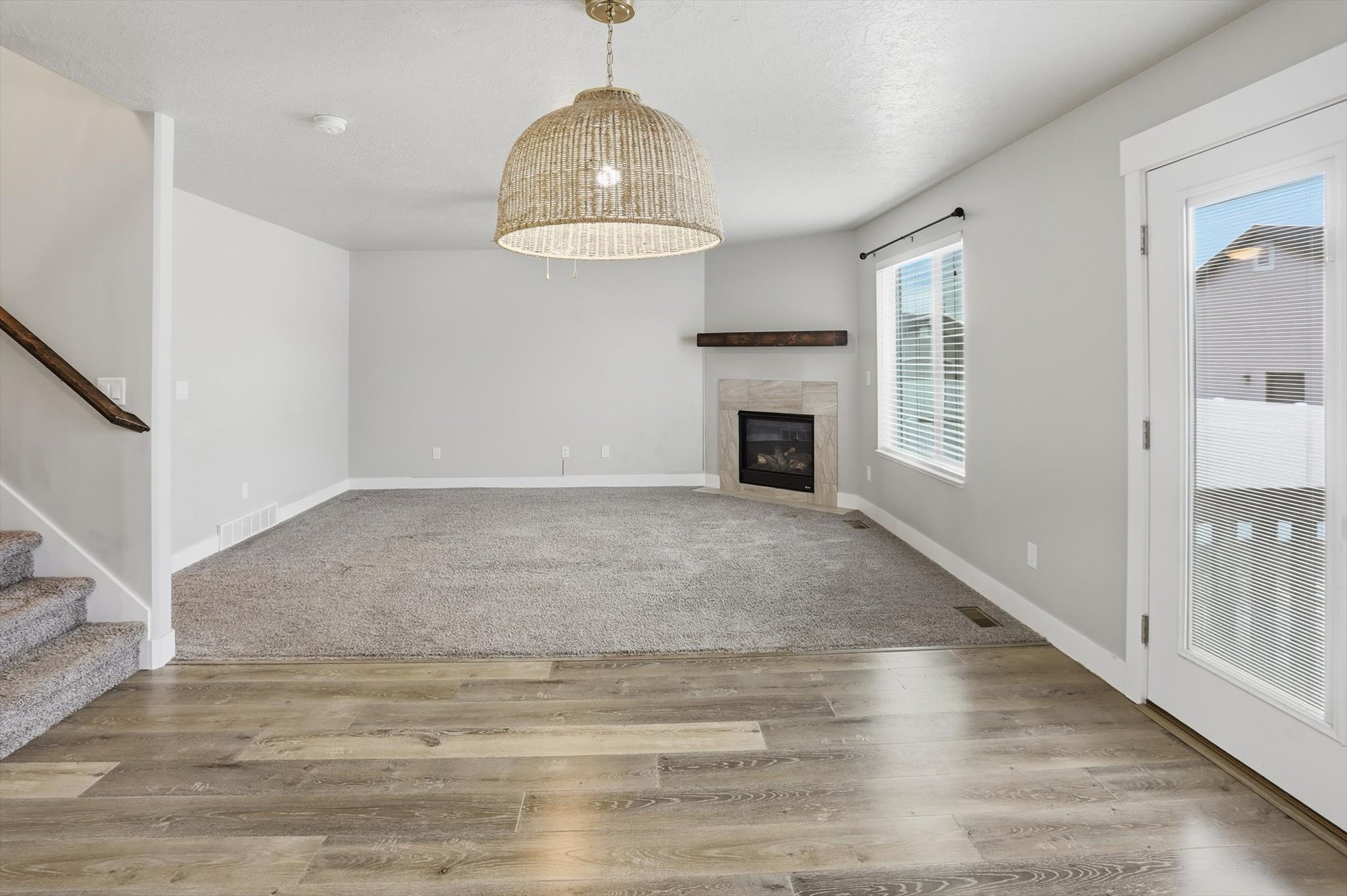 Unfurnished living room with a tile fireplace, light wood-style floors, and a textured ceiling