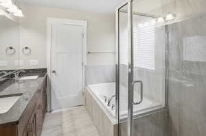 Bathroom with double vanity, a shower stall, and a garden tub