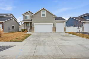 View of front of home with covered porch, driveway, stucco siding, a garage, and a gate