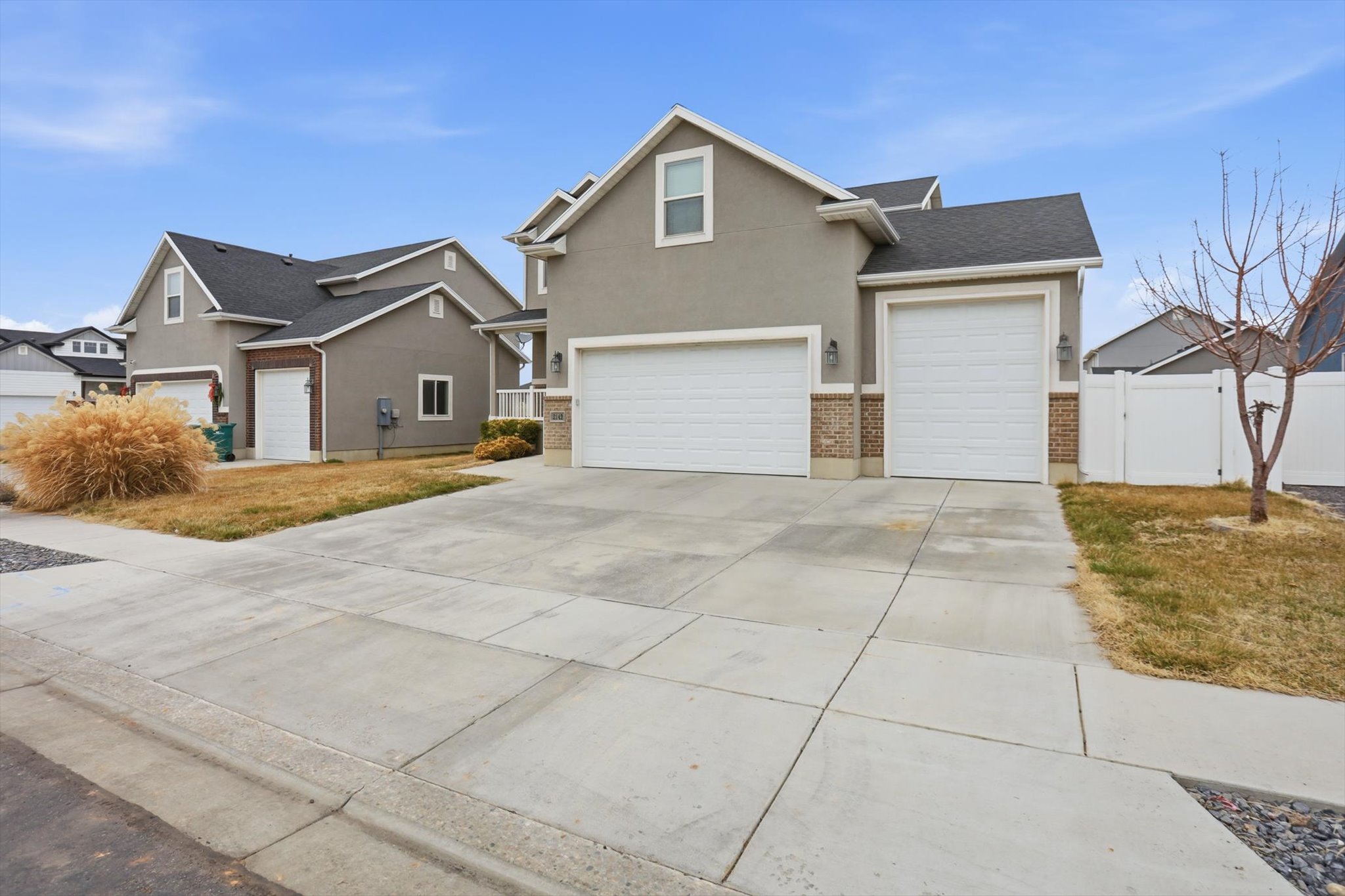 View of front facade featuring a gate, driveway, brick siding, stucco siding, and a garage