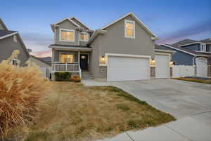 View of front of house with covered porch, stucco siding, and concrete driveway