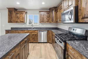 Kitchen featuring stainless steel appliances, dark stone counters, recessed lighting, light wood-style floors, and wood finish cabinets