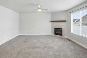 Unfurnished living room featuring light colored carpet, a ceiling fan, and a premium fireplace