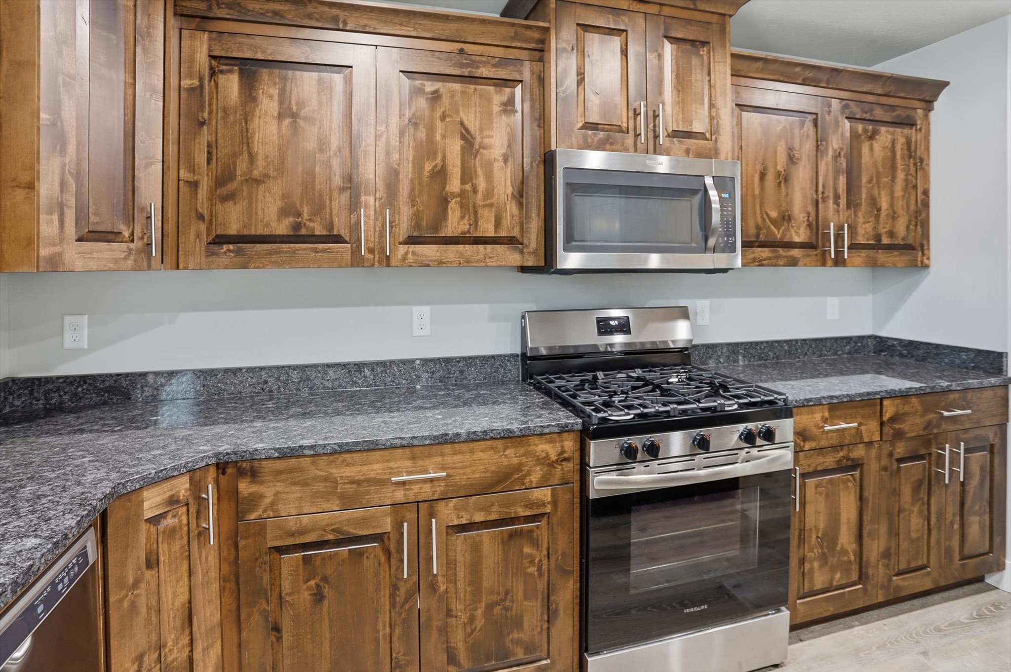 Kitchen featuring stainless steel appliances, dark stone counters, and wood finish cabinetry