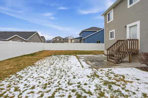 Yard layered in snow featuring a fenced backyard, a residential view, and a patio