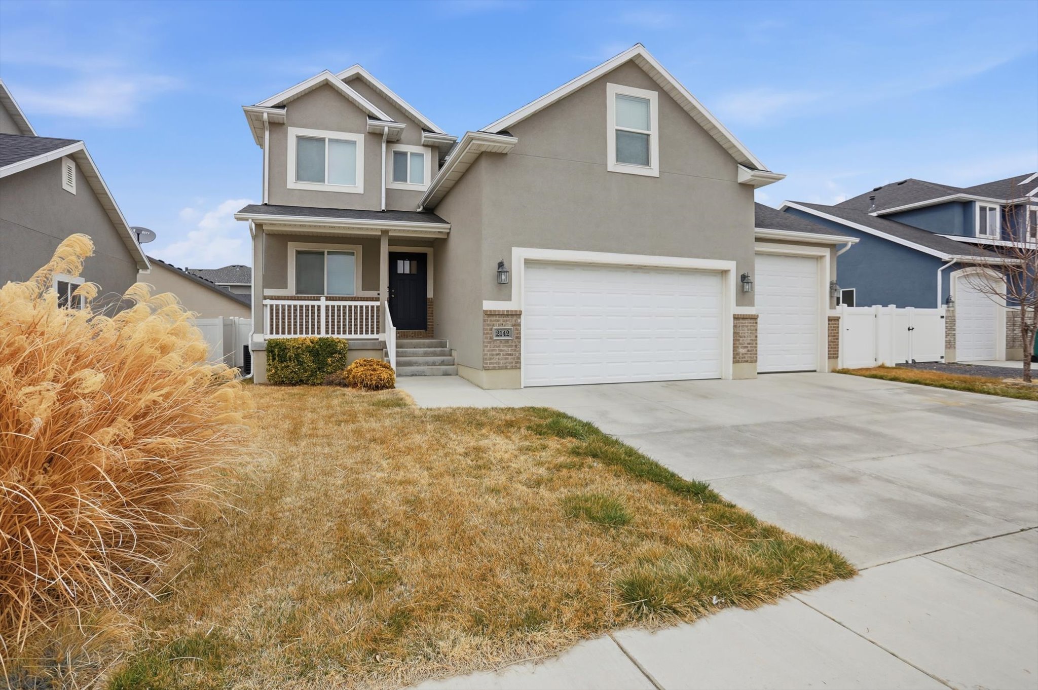 View of front of house featuring a porch, stucco siding, driveway, and a garage