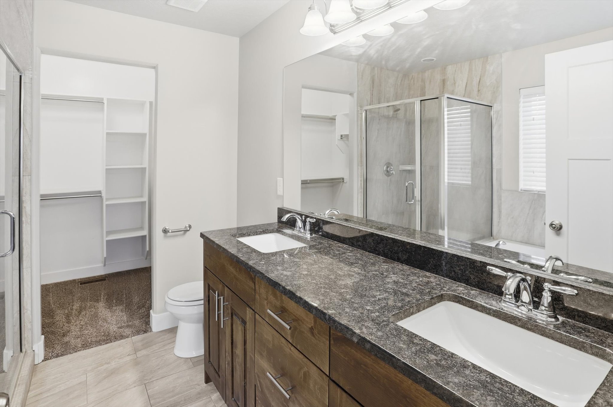 Bathroom featuring a walk in closet, a shower stall, double vanity, a bath, and light carpet