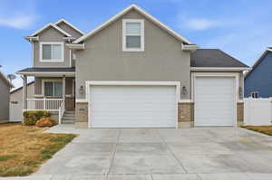 View of front of property with a porch, brick siding, stucco siding, and driveway