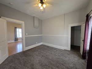 Unfurnished bedroom with carpet flooring, a walk in closet, and a ceiling fan