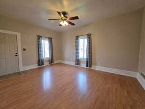 Spare room featuring light wood-style flooring, plenty of natural light, a ceiling fan, and a textured ceiling