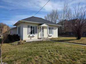 View of front of property with a front yard and a shingled roof
