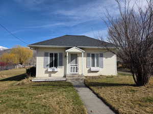 Bungalow-style house featuring a shingled roof and a front lawn