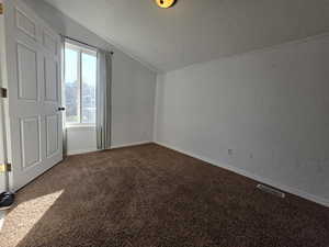 Bonus room with a textured wall and dark colored carpet