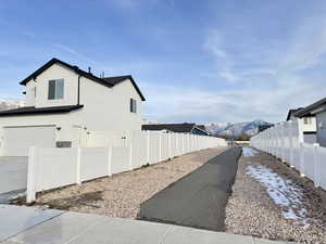 View of side of home with a mountain view, stucco siding, and a garage