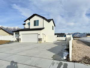 View of property exterior with a mountain view, an attached garage, stucco siding, driveway, and a gate