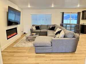 Living room with light wood-style flooring, a glass covered fireplace, and a textured ceiling