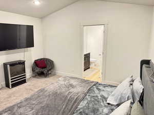 Bedroom featuring a textured ceiling, light colored carpet, and ensuite bath