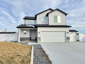View of front of house featuring a gate, covered porch, concrete driveway, a garage, and stucco siding