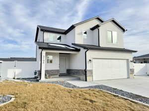 View of front facade featuring a gate, a garage, stone siding, driveway, and stucco siding