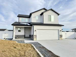 View of front facade featuring a gate, driveway, an attached garage, covered porch, and stucco siding