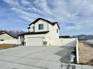 View of home's exterior with a mountain view, a gate, an attached garage, concrete driveway, and stucco siding
