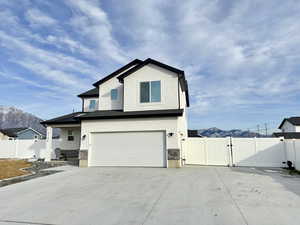 View of front of property featuring a gate, a mountain view, stucco siding, and an attached garage