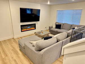 Living area with light wood-style floors and a glass covered fireplace