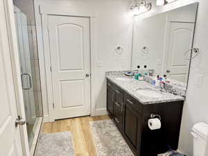 Full bath featuring double vanity, light wood-type flooring, and a stall shower