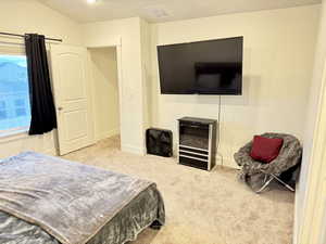 Bedroom with light carpet and lofted ceiling