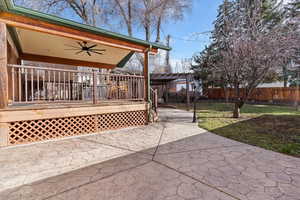 Fenced backyard with a ceiling fan, a deck, and a patio