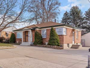 View of front of home with entry steps, brick siding, a front yard, and driveway
