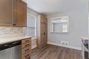 Kitchen with stainless steel appliances, dark wood-type flooring, wood finish cabinets, and backsplash