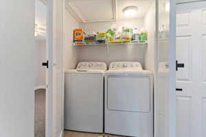 Laundry room with washing machine and dryer and light colored carpet