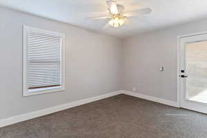 Empty room with dark carpet and a ceiling fan