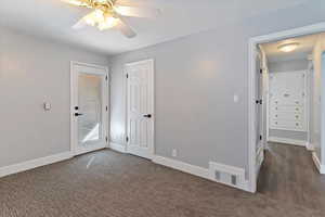 Unfurnished bedroom featuring a ceiling fan and dark carpet