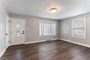 Entrance foyer with dark wood-style flooring and a textured ceiling