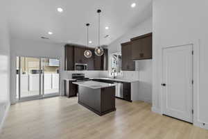Kitchen with dark wood finish cabinets, a center island, tasteful backsplash, decorative light fixtures, and vaulted ceiling