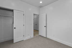 Unfurnished bedroom featuring light colored carpet, recessed lighting, and a closet