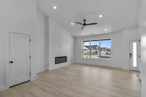 Unfurnished living room with a ceiling fan, a glass covered fireplace, light wood finished floors, and recessed lighting