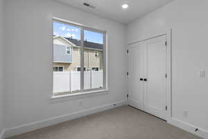 Unfurnished bedroom featuring light colored carpet, a closet, and recessed lighting
