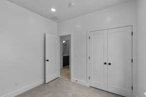 Unfurnished bedroom with light carpet, a closet, and recessed lighting