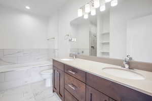 Full bath with double vanity, a stall shower, a bath, and recessed lighting