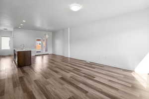 Unfurnished living room featuring dark wood finished floors, a chandelier, and a textured ceiling