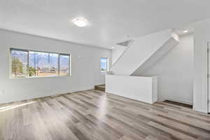 Unfurnished living room featuring light wood-style flooring and a textured ceiling