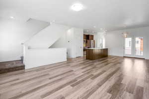 Unfurnished living room featuring light wood-type flooring and hanging lights