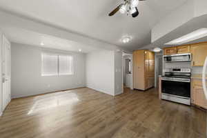 Kitchen with a ceiling fan, stainless steel appliances, light countertops, light wood finish cabinets, and dark wood finished floors