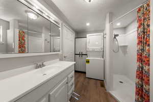 Full bathroom featuring a shower stall, dark wood-type flooring, stacked washer / drying machine, vanity, and recessed lighting