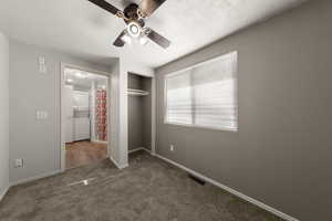 Unfurnished bedroom with dark carpet, a closet, and ceiling fan