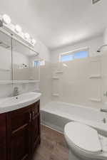 Full bath with vanity, tub / shower combination, a textured ceiling, and dark wood finished floors