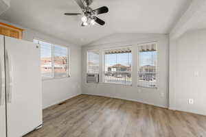 Spare room with ceiling fan, vaulted ceiling, light wood-style flooring, and cooling unit